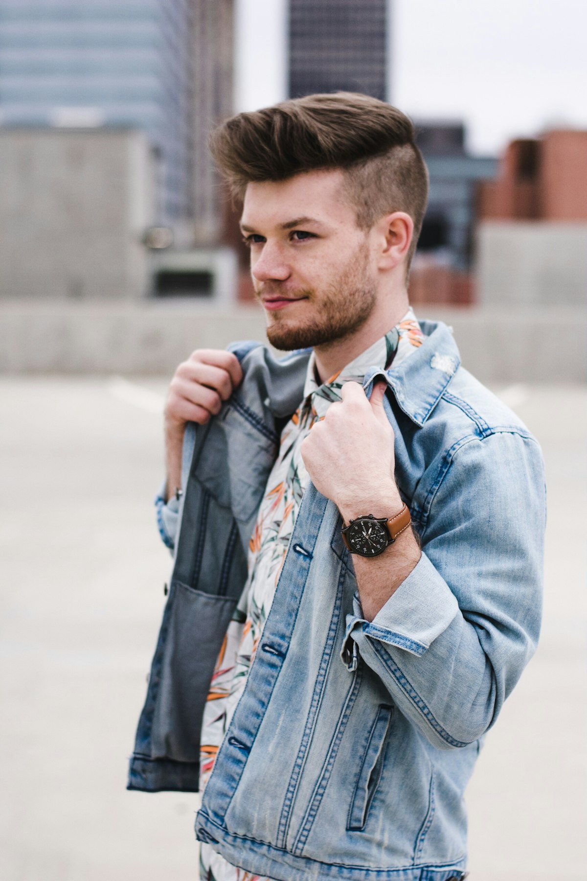 Adulto jovem com jaqueta jeans clara sobre camisa estampada